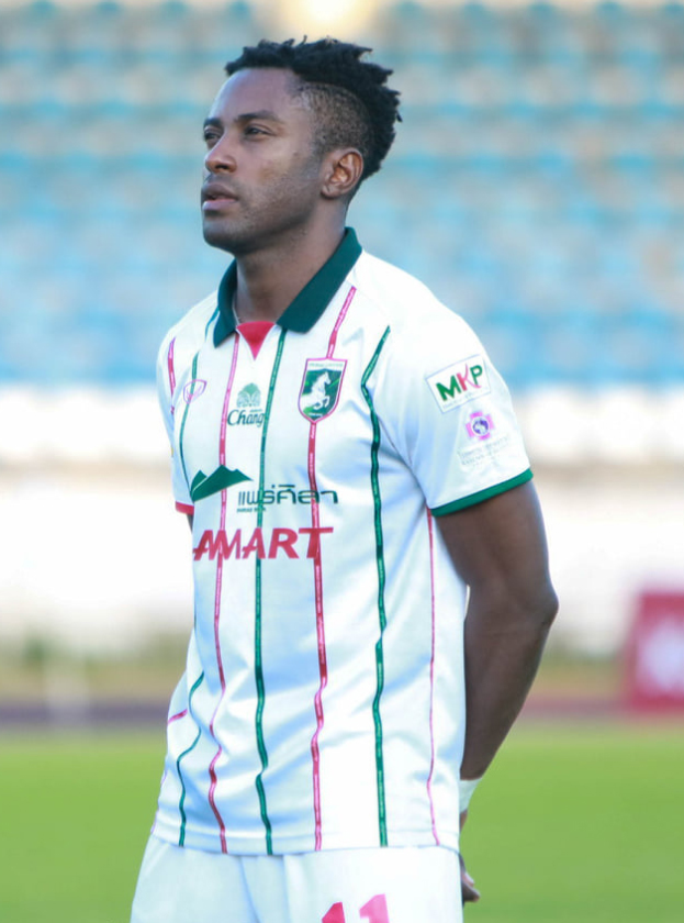 Der ghanaische Fussballspieler Emmanuel Adebayor steht auf einem Fussballfeld und trägt ein weisses und grünes T-Shirt und Shorts.