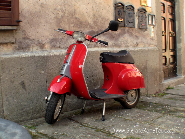 Ein roter E-Scooter steht vor einem Haus mit Tür und Fenstern auf einer Straße mit Text unten.