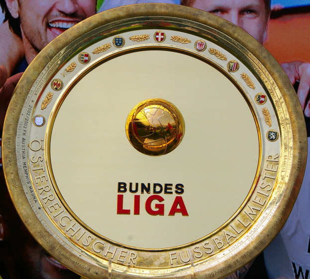 Goldener Schild mit 'Bundesliga'-Text, gehalten von einem Mann mit einem Banner im Hintergrund mit drei Personen.