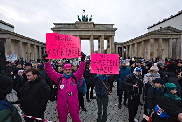 Eine Gruppe von Menschen protestiert vor dem Brandenburger Tor in Berlin mit Schildern gegen die Anti-Nazis-Bewegung der deutschen Regierung.