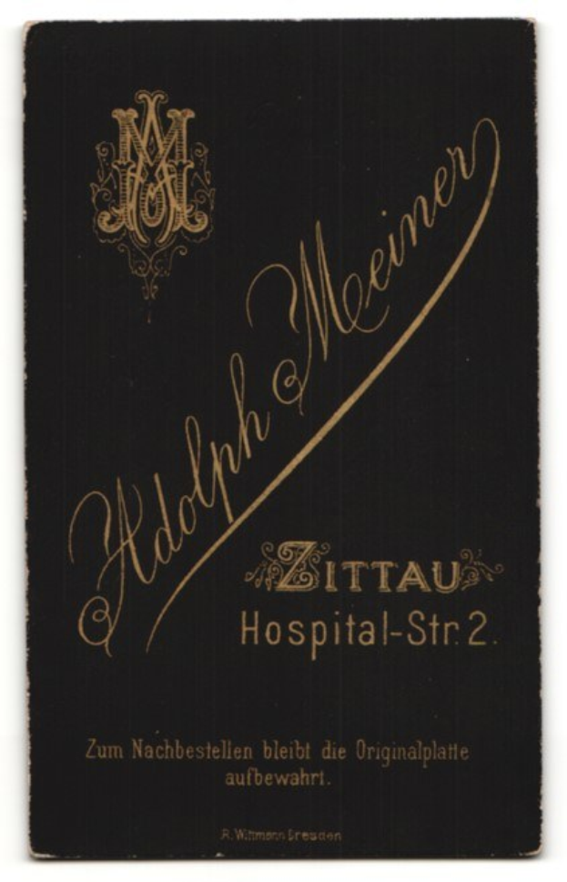 Schwarzes Buch mit goldenen Lettern, das "Adolph Meiner - Zittau Hospital-Str 2" auf einem weißen Hintergrund zeigt.