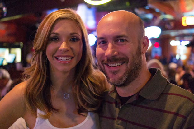 Ein Paar, das strahlend vor einem unscharfen Hintergrund steht.