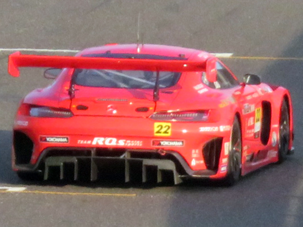 Roter Porsche 911 GTS Rennauto auf einer Rennstrecke mit aerodynamischem Design, großer Heckflosse und schwarzen Rädern.