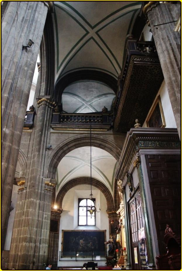 Ein prächtiger Innenraum eines Palastes mit verzierten Schränken, beleuchteten Säulen, Wandskulpturen, einem großen Rahmenbild und einer von der Decke hängenden Lampe.