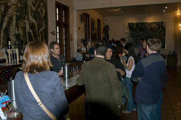 Eine Gruppe von Menschen steht an einer Bar-Theke mit einem Barkeeper dahinter.