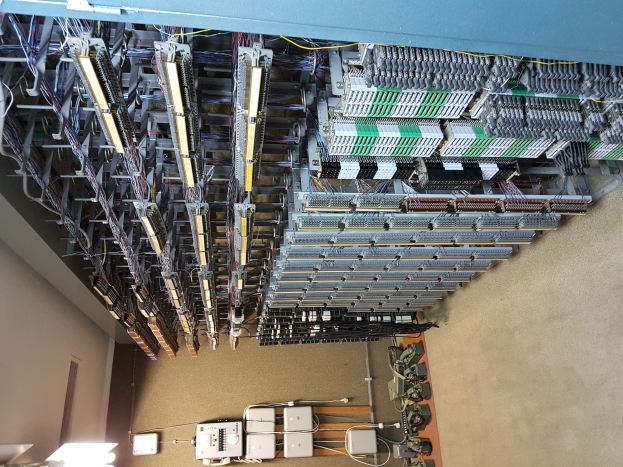 Ein geräumiger Raum voller Numerous wires and electronic devices on the floor, with a wall on the left side, resembling a data center with various servers and interconnected cables.