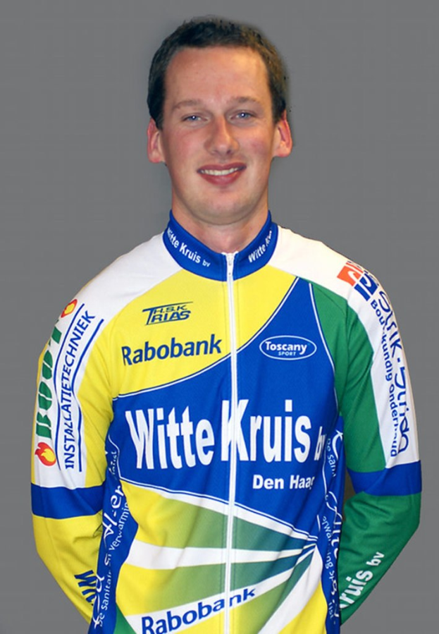 Ein männlicher Athlet posiert für ein Foto und trägt ein Hemd mit mehreren Sponsoren-Logos.