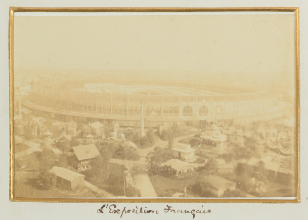 Altes Schwarz-Weiß-Foto eines Stadions in einer städtischen Umgebung mit sichtbaren Gebäuden, Bäumen und Strommasten; Text ist am unteren Bildrand vorhanden.