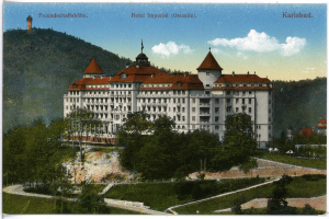 Eine alte Postkarte des Hotel Imperial in Karlsbad, Deutschland, zeigt ein großes Gebäude mit Fenstern, umgeben von Bäumen, Pflanzen, Gras, einem Pfad, einer Baumgruppe, Hügeln und einem bewölkten Himmel, mit Text oben.