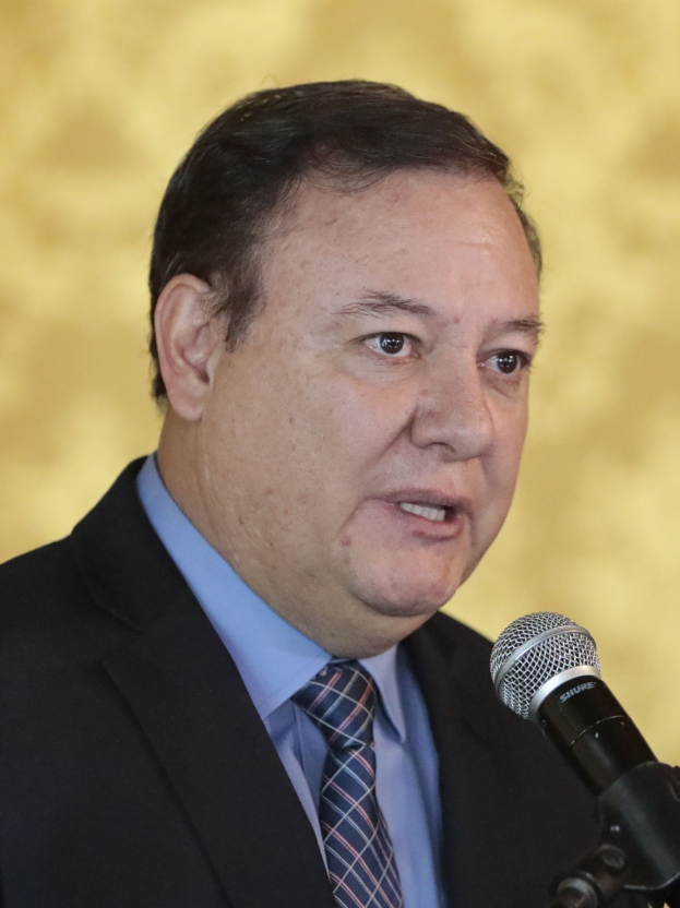 Ein Mann im Anzug und mit Krawatte spricht in ein Mikrofon und wird als Generalstaatsanwalt identifiziert.