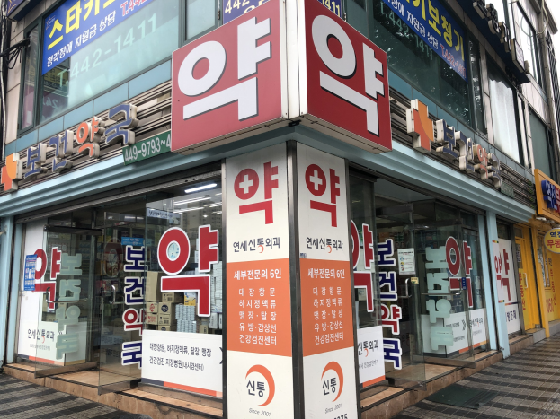 Außenansicht einer modernen Glasfassade einer Apotheke in Seoul, Südkorea, mit Text, der darauf hinweist, dass es die erste Apotheke der Stadt ist.