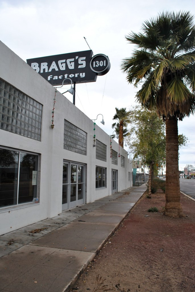 Ein Gebäude mit einer Flagge oben, auf der steht "Braggs Factory", umgeben von Bäumen.