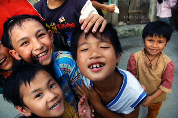 Kinder, die mit einer Straße und einer Wand im Hintergrund stehen und lächeln.
