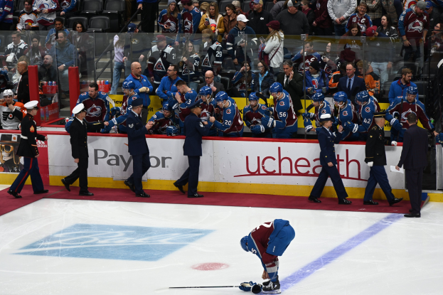 Hockeyspieler auf dem Eis umgeben von Leuten mit Mützen, die Stöcke halten, mit Zuschauern im Hintergrund und Arena-Böden mit "Colorado Avalanche vs San Jose Sharks - 3/24/15 NHL Pick, Odds, and Prediction".