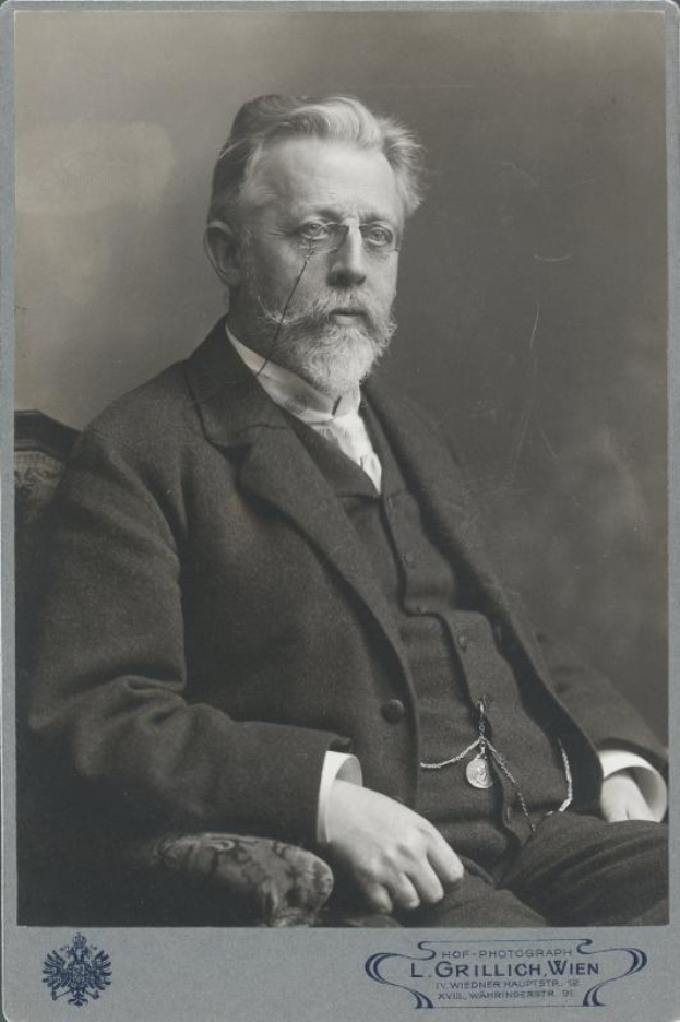 Schwarz-weißes Porträt eines bärdigen Mannes mit Brille, der in einem Stuhl sitzt, beschriftet mit "L. Grillich Wien, der Gründer der deutschen Revolution."