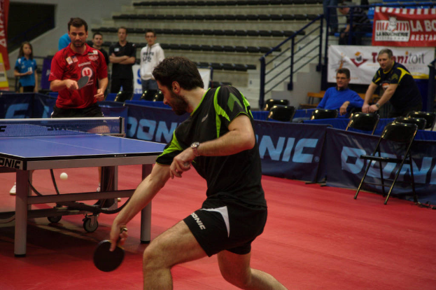Eine Gruppe von Menschen in verschiedenen Farben wie schwarz, weiß und blau sitzt um einen Tisch mit einem Spiel im Hintergrund, Stühle und eine Treppe.