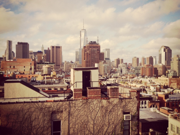 Eine Luftaufnahme einer Stadt mit zahlreichen Gebäuden, die über die Landschaft verstreut sind, unter einem bewölkten Himmel.