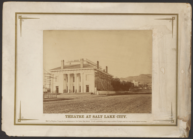 Schwarz-weisses Foto des Theaters in Salt Lake City mit einem zentralen Gebäude, umgeben von Bäumen und Hügeln, und Text unten.