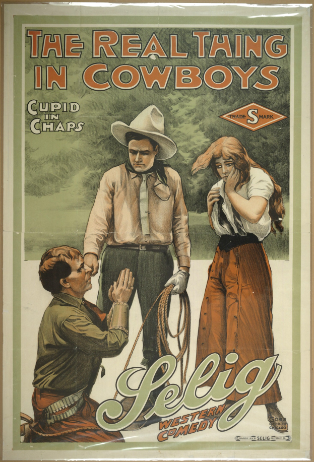 Plakat an einer Wand mit drei Personen, zwei Männer mit Cowboyhüten und eine Frau in einem langen Kleid, mit der Schrift "The Real Thing in Cowboys" in fetter schwarzer Schrift auf einem hellgelben Hintergrund.