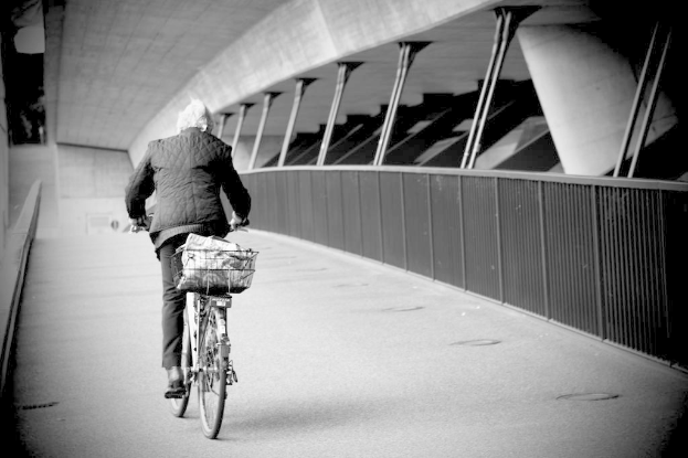 Eine Person fährt auf einem Weg mit Fenstern auf der rechten Seite und einer Wand im Hintergrund.