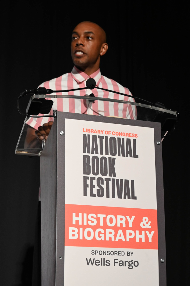 Ein Mann steht an einem Podium mit einem Mikrofon und spricht bei einer Abendveranstaltung mit dem Titel "National Book Festival History & Biography".