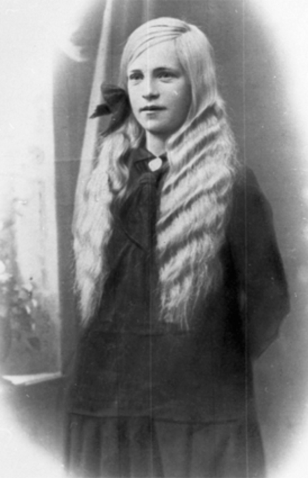 Ein altes Schwarz-Weiß-Foto einer Frau in einem Nerzpelz, mit einem ordentlichen Dutt und einem konzentrierten Gesichtsausdruck.