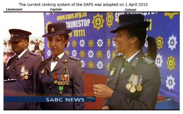 Gruppe von Menschen in Uniformen und Hüten mit einem Banner, Text oben und unten lautet "Das aktuelle Ranglistensystem der SAP wurde am 1. April 2010 eingeführt."