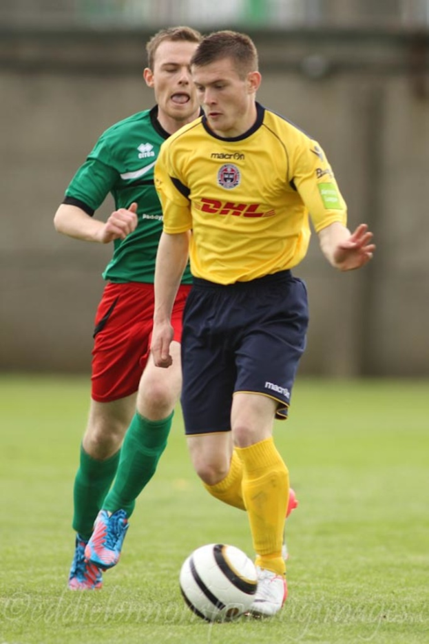 Zwei Männer beim Fußballspiel auf einem grünen Rasen mit einem Ball, mit unscharfem Hintergrund und Text unten.