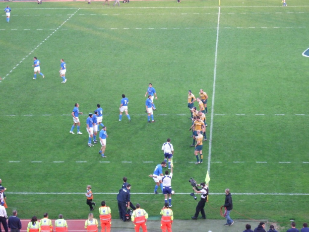 Einige Menschen auf einem Fußballfeld, einer hält eine Videokamera.