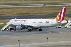 Ein Airbus A320-200 der Germanwings auf dem Frankfurter Flughafen geparkt, mit Fahrzeugen, Verkehrskegeln, Pfosten und Gras im Hintergrund.