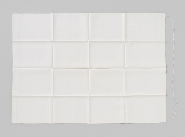 Ein weißes Tuch mit einem hellgrauen Faden auf einem neutralen grauen Hintergrund.