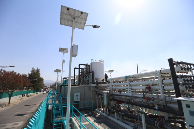 Großes industrielles Gebäude mit ausgedehnten Rohrleitungen, Solarpanelen, Geländern und Infrastruktur in der Umgebung, vor einem klaren blauen Himmel auf einem Hügel in Kalifornien