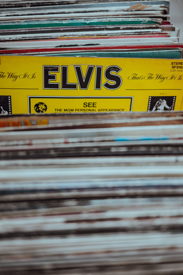Ein ordentlicher Stapel Elvis-Presley-Platten mit lesbaren Titeln auf einem leicht unscharfen Hintergrund.