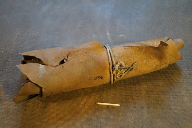 Papiertüte, die wie eine Granate aussieht, mit einem Seil zusammengebunden, mit einer Zigarette daneben auf einem Tisch.