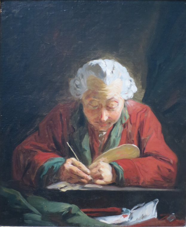 Eine ältere Frau sitzt an einem Tisch und schreibt konzentriert auf ein Blatt Papier mit einem Stift, umgeben von einem Foto Rahmen, der darauf hindeutet, dass sie sich in ihrem eigenen Zuhause befindet.